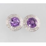 A pair of 14ct white gold circular amethyst and diamond earrings, the brilliant cut amethysts