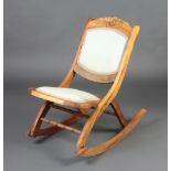 A Victorian carved and bleached mahogany folding campaign rocking chair, the seat and back
