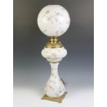 A Victorian brass oil lamp reservoir raised on an opaque and floral glass base together with a