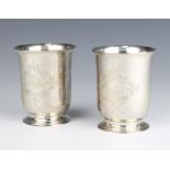 A pair of Victorian silver beakers of plain form with chased scroll cartouche and monogram, London