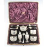 A Victorian repousse silver 7 piece condiment with scroll and floral decoration and 5 matching