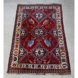 A red and blue ground Persian Qashqai rug with central medallion decorated 4 birds within floral and