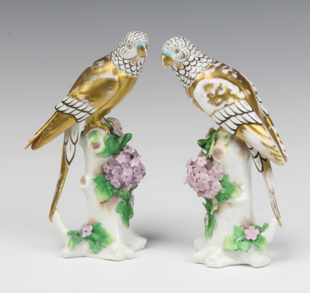 A pair of Sampson figures of budgerigars sitting on floral encrusted tree stumps 17cm Both have