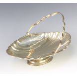 A scallop silver basket with swing handle raised on an oval pedestal foot 500 grams The hallmarks