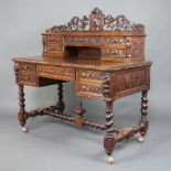 A Victorian heavily carved oak writing table, the raised superstructure with pierced and carved 3/