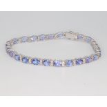An 18ct white gold tanzanite and diamond line bracelet, the oval tanzanites approx. 9.22ct, the