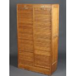 A 1930's light oak 2 section filing cabinet fitted shelves enclosed by a tambour shutter 148cm h x