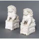 A pair of antique style Chinese carved white marble figures of shi shi raised on scroll bases 62cm