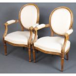 A pair of beech framed French style open arm salon chairs with upholstered seats and backs raised on