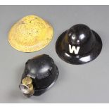 A fire watchers black painted helmet marked W (no liner), a yellow painted steel helmet (no liner