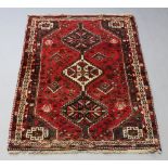 A red ground Afghan rug with 3 stylised diamonds to the centre 170cm x 121cm