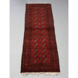 A red ground Afghan runner with 26 octagons to the centre within a multi row border 240cm x 82cm