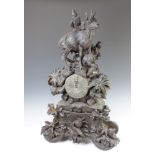 A carved Swiss clock case surmounted by a figure of a goat, the base decorated acorns and 2 game