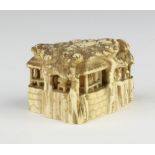 A Meiji period Japanese carved ivory Netsuke in the form of a building with figures seated inside,