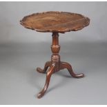 A Georgian country oak tea table with pie crust edge raised on a turned urn column support with