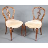 A pair of Victorian carved mahogany spoon back dining chairs with overstuffed seats, carved and