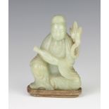 A jade figure of Guan Yin, c.1900, seated and carved in the grey-green stone holding the Vase of the