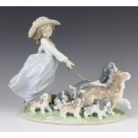 A Lladro figure of a young lady walking 2 dogs and 5 puppies 6784 30cm