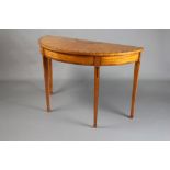 A Sheraton style inlaid and crossbanded satinwood demi-lune table raised on square tapered supports,