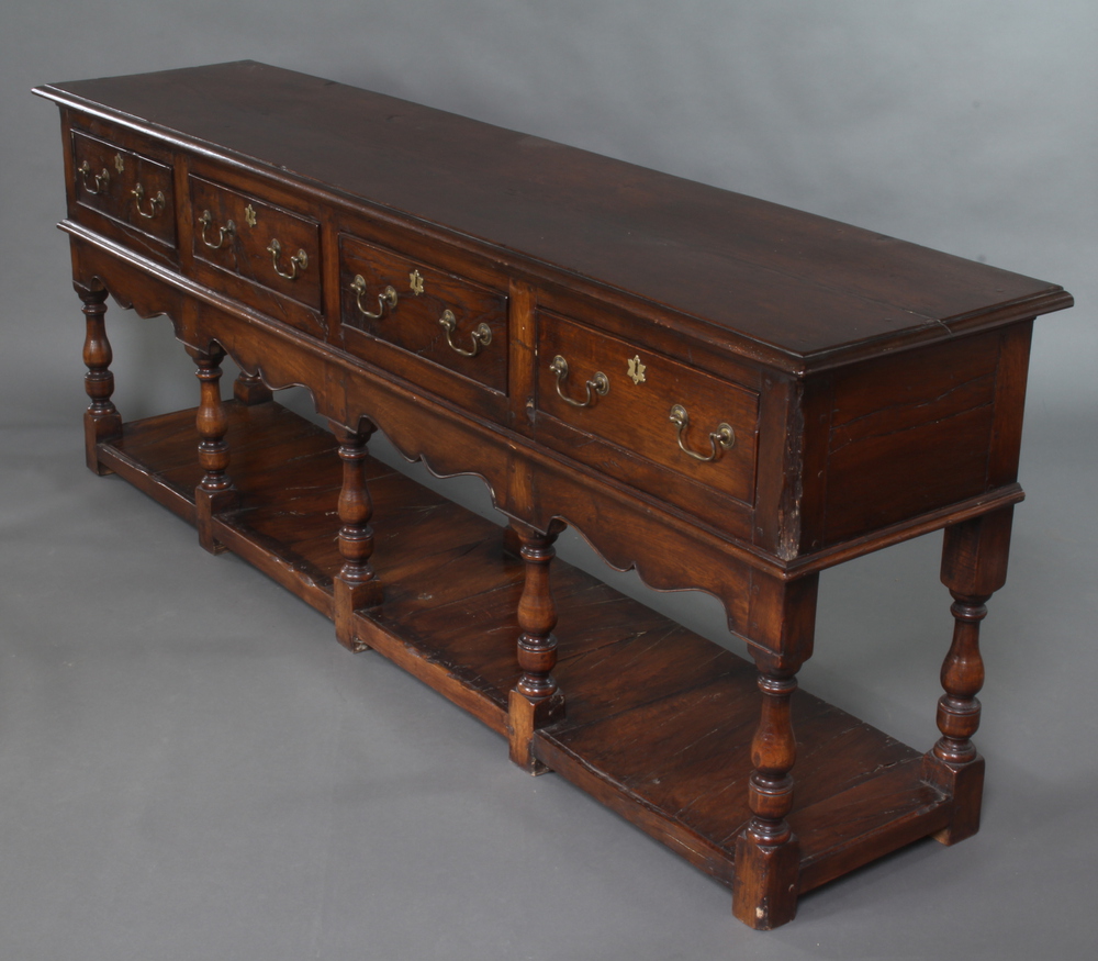 A 17t/18th Century style oak dresser base fitted 4 drawers with cupboard beneath, raised on turned