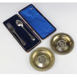 A pair of silver plated commemorative coin set dishes and a ditto christening spoon and fork