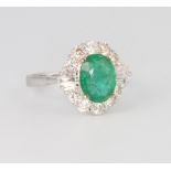 An 18ct white gold diamond and emerald cluster ring, the centre emerald surrounded by brilliant