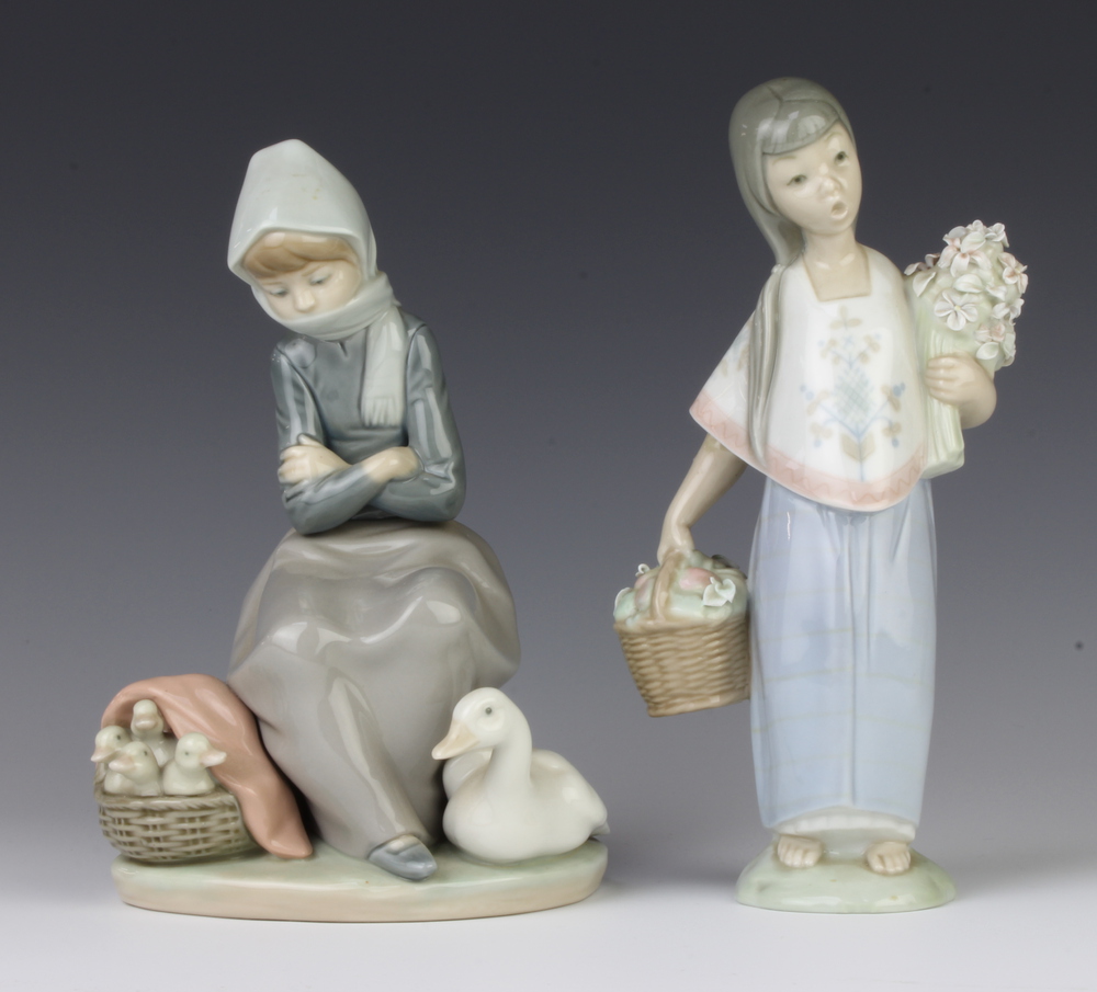 A Lladro figure of a young girl holding a basket of fruit 22cm, a ditto of a seated goose girl