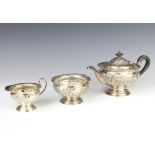 An Edwardian repousse silver bachelor tea set comprising teapot, sugar bowl and cream jug