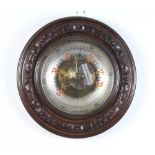 An Edwardian aneroid barometer and thermometer contained in a carved mahogany circular case 34cm