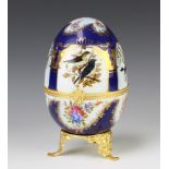 A 20th century painted porcelain gilt metal mounted egg decorated with birds and flowers 23cm