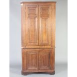 An 18th Century oak double corner cabinet with moulded cornice, both sections fitted shelves