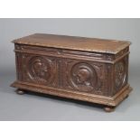 An 18th Century style carved oak coffer with hinged lid, the front panel carved figures of warriors,