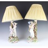 A pair of German porcelain table lamps in the form of a fete gallant couple with applied flowers,