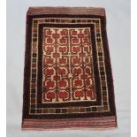 A Belouche brown, red and white ground rug with central field and geometric design within a 3 row
