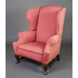 A Georgian style mahogany winged armchair upholstered in red material with turned stretcher,