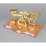 A pair of brass letter scales raised on a mahogany stand with 3 weights