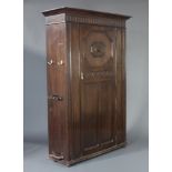 A 1920's oak hall cupboard with moulded cornice and arcaded decoration enclosed by a panelled