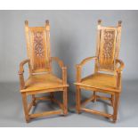 A pair of Arts and Crafts style carved oak high back open arm throne chairs with solid seats