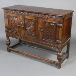 An Ipswich style carved oak cabinet enclosed by 3 panelled doors with arcaded decoration, raised
