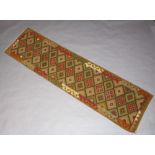 A tan, green and brown ground Maiman Kilim runner with diamonds to the centre 293cm x 80cm