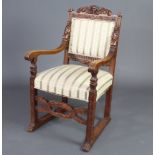 An Italian carved oak open arm chair, the crest carved a cherub, the arms carved figures of kneeling