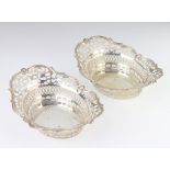 A pair of Edwardian pierced and repousse silver bon bon dishes with scroll decoration and mask