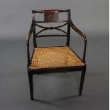 A Regency style lacquered bar back bedroom chair with X framed back and woven cane seat, raised on