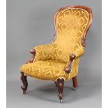 A Victorian mahogany show frame armchair upholstered in yellow material, raised on cabriole supports