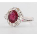 An 18ct white gold oval, treated ruby and diamond cluster ring, the centre stone approx. 2.96ct