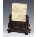An early 20th Century small ivory table screen, almost square and carved in relief with a