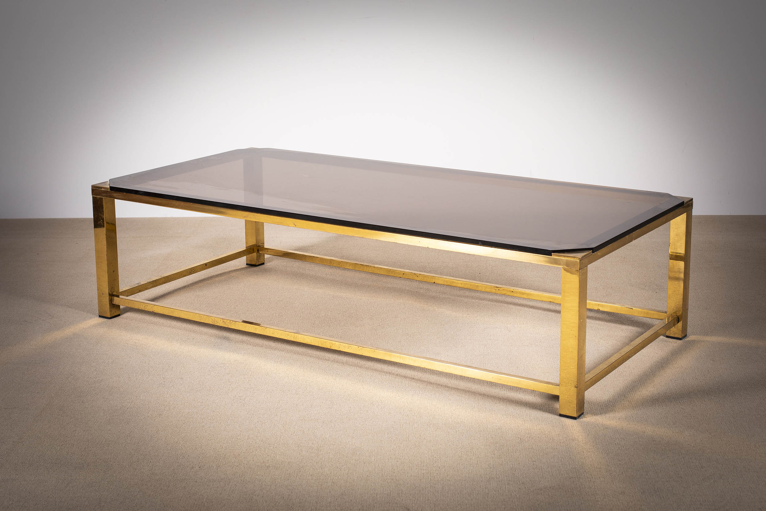 A GILT METAL RECTANGULAR LOW TABLE, FRENCH 1970s, with smoked glass, 135cm x 65cm x 35cm