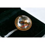 A 9CT YELLOW GOLD CIRCULAR HEADED RING set with an Essex type crystal intaglio cut with a peacock,