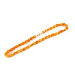 A POLISHED BUTTERSCOTCH AMBER NECKLACE comprising forty uniform beads with a bone clasp, 20 ins