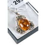 AN OVAL AMBER INSET PENDANT with floral silver mount, stamped 925 on a silver neckchain.